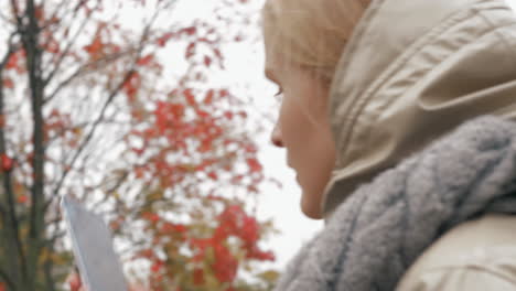 Woman-taking-picture-of-rowan-tree-during-autumn-walk-with-baby