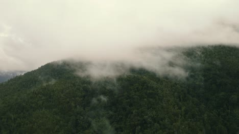 alejamiento aéreo y toma en órbita de una montaña cubierta de niebla y nubes, en la costa oeste de nueva zelanda