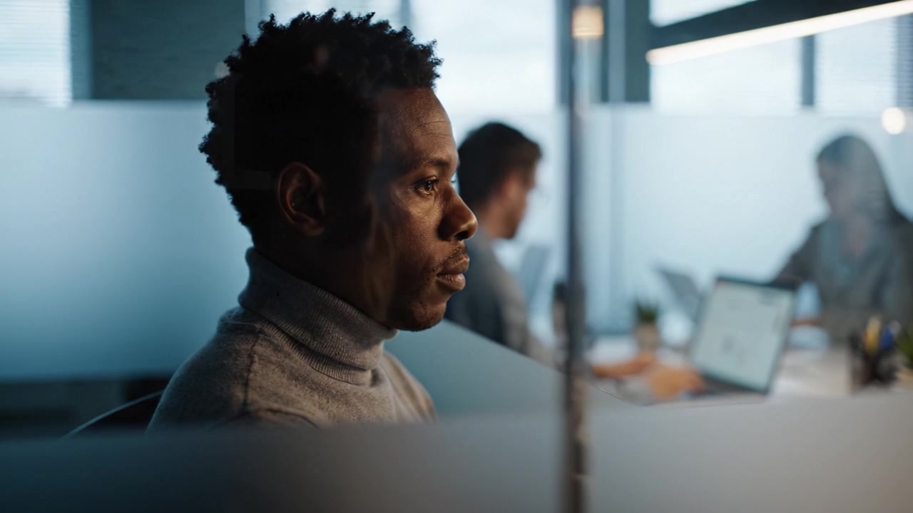 Focused Professional in Modern Office Environment, Engaged in Work Activities Amidst Colleagues in a Collaborative Workspace Setting
