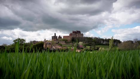 wide angle view timelapse of biron castle with vegetation and flowers in foreground