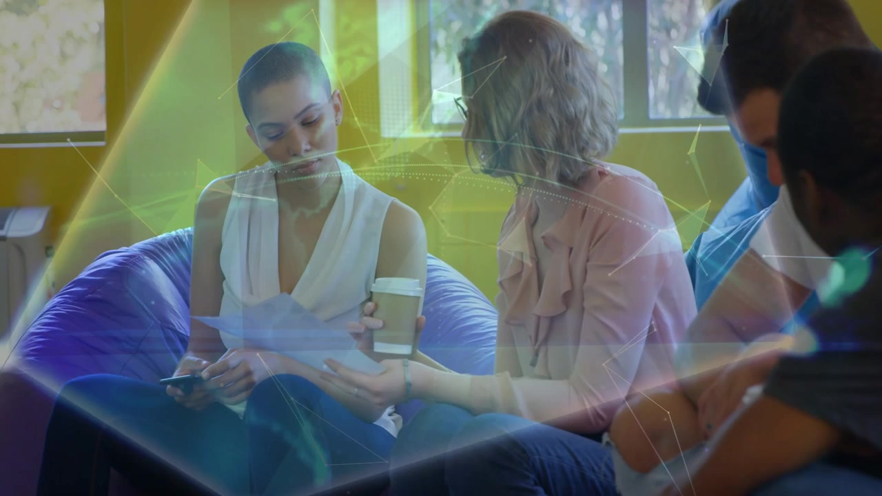 Two women exchanging papers and pointing as holo globe growing over purple sofa for business review
