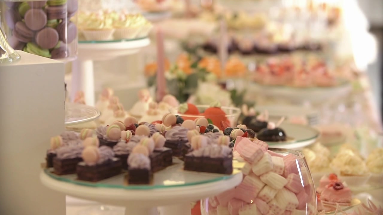 Tavolo da dessert elegante con torte e pasticcini colorati.