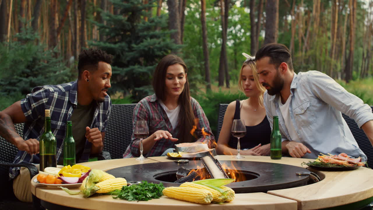 Amici che preparano il pesce al barbecue all'aperto. Amici che discutono il processo di cottura.