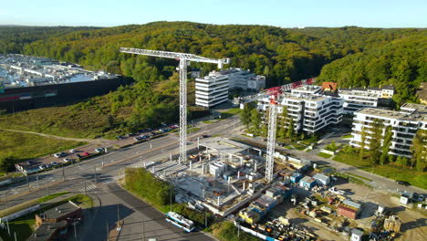 aerial drone orbit around construction site with tall tower cranes among urban buildings