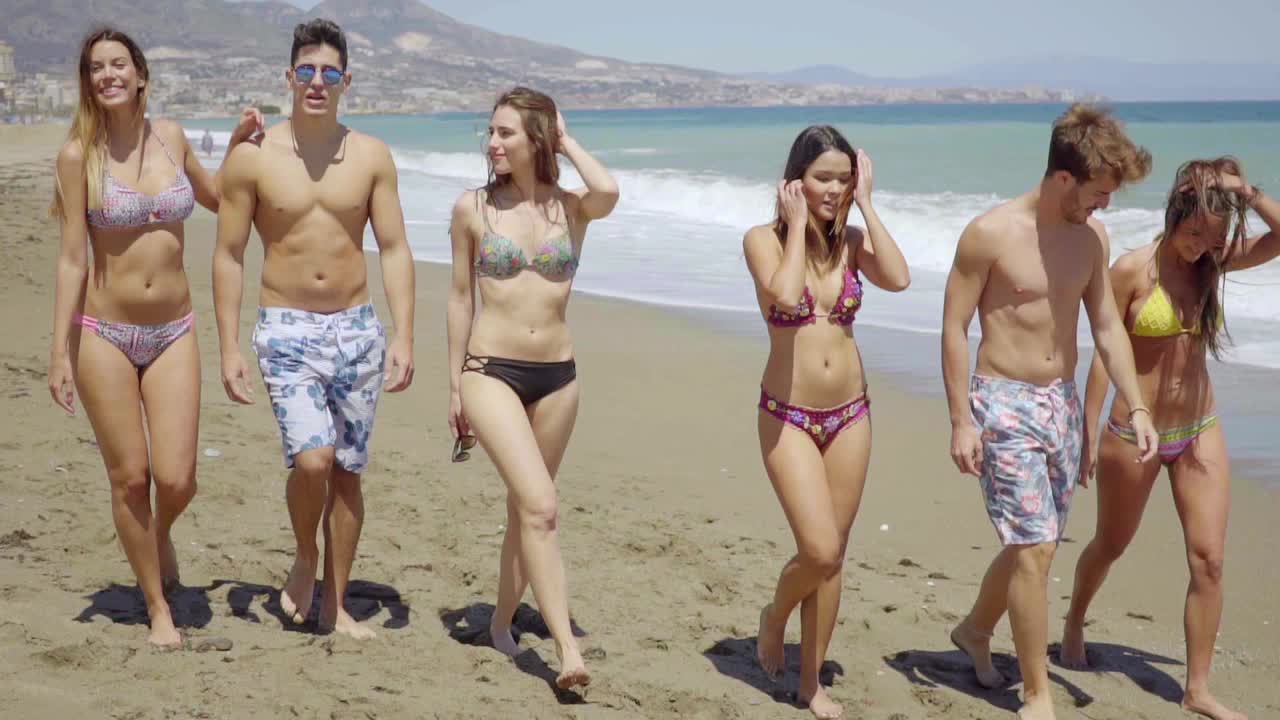 Grupo de amigos caminando juntos en una playa soleada