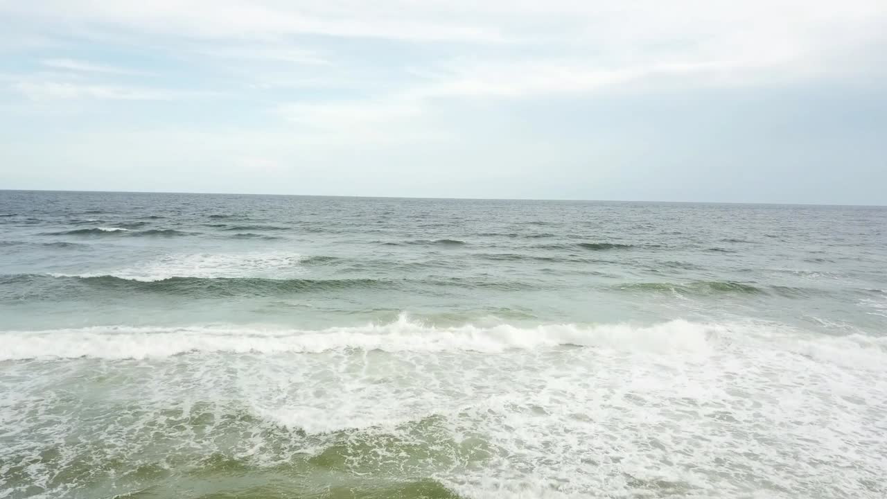 흐린 푸른 하늘 배경으로 흰색 거품 파도가 튀는 - 공중 드론 샷