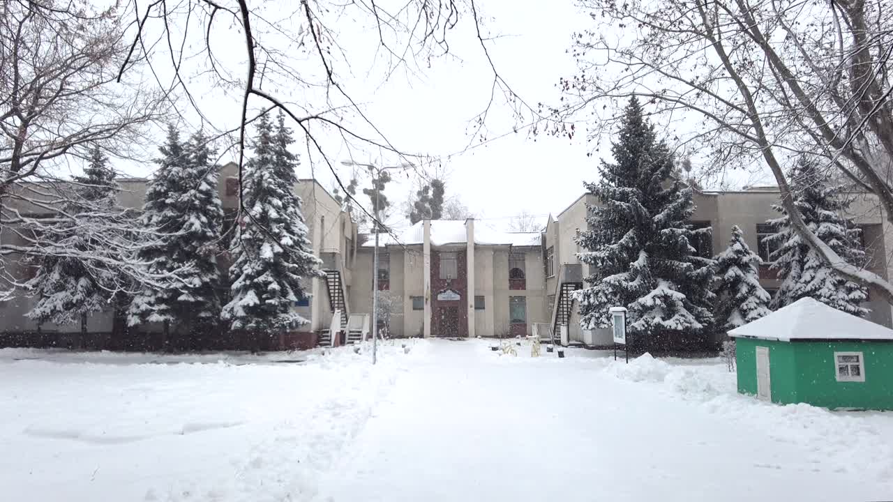 An apartment complex is blanketed in snow during winter. The surrounding trees add beauty to the scene, creating a serene and peaceful atmosphere