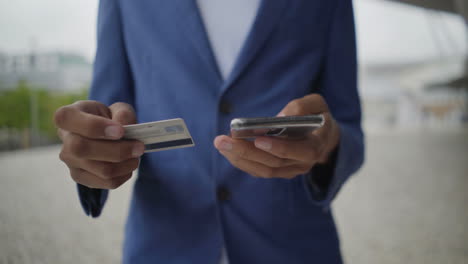 african american man typing card number on smartphone.