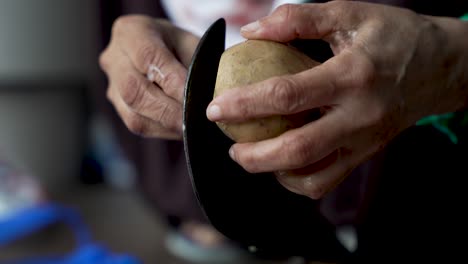 Close-up-of-aged-hands-peeling-a-potato-with-a-traditional-Indian-Aruvamanai-cutter