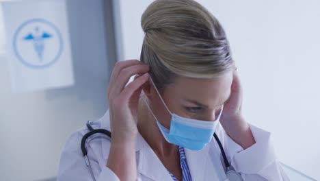 portrait of caucasian female doctor putting face mask on