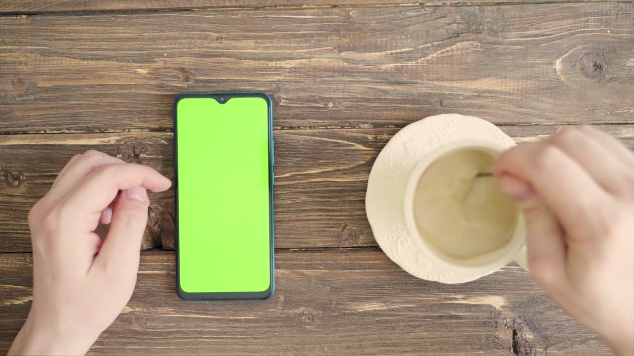 manos masculinas con un teléfono inteligente con una llave de croma en la mesa. vista desde arriba