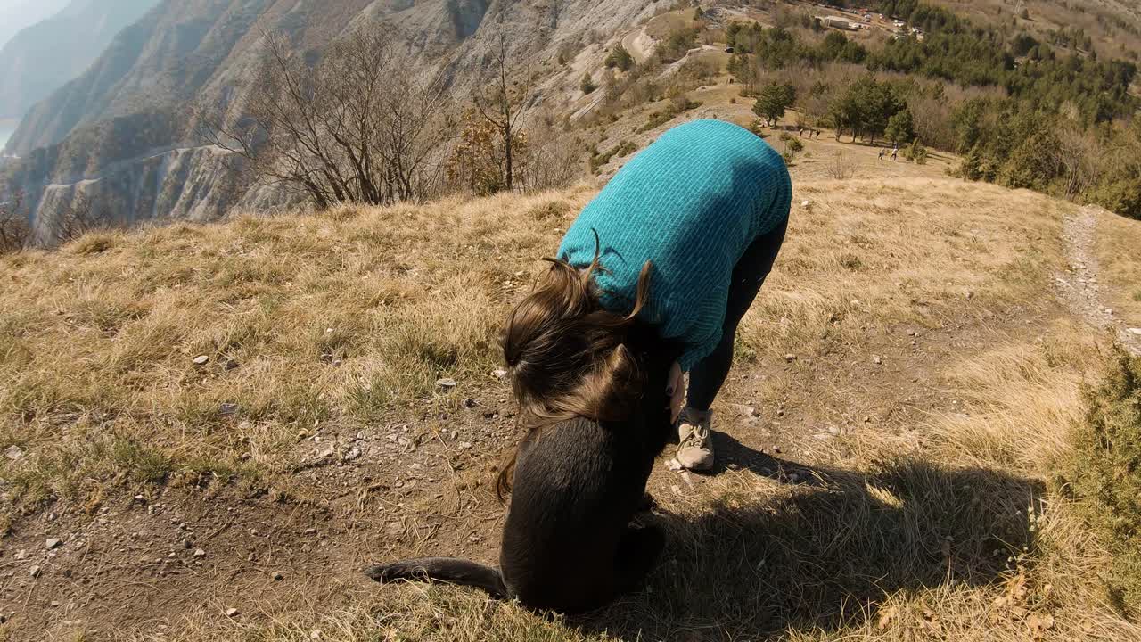 chica abrazando con perro labrador negro en una montaña en otoño