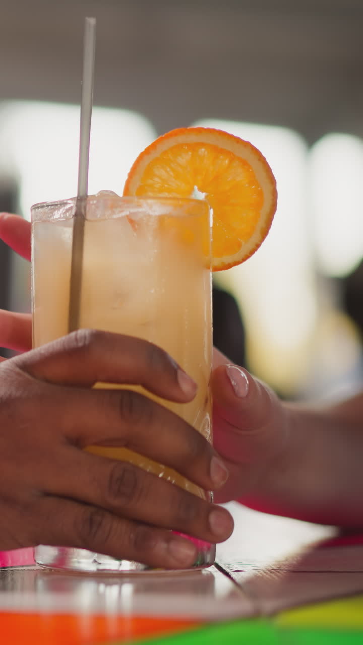 el camarero sirve un cóctel para el invitado en un bar de primer plano. un hombre afroamericano empuja un vaso con una bebida exótica a una joven turista. el camarero serve una bebida