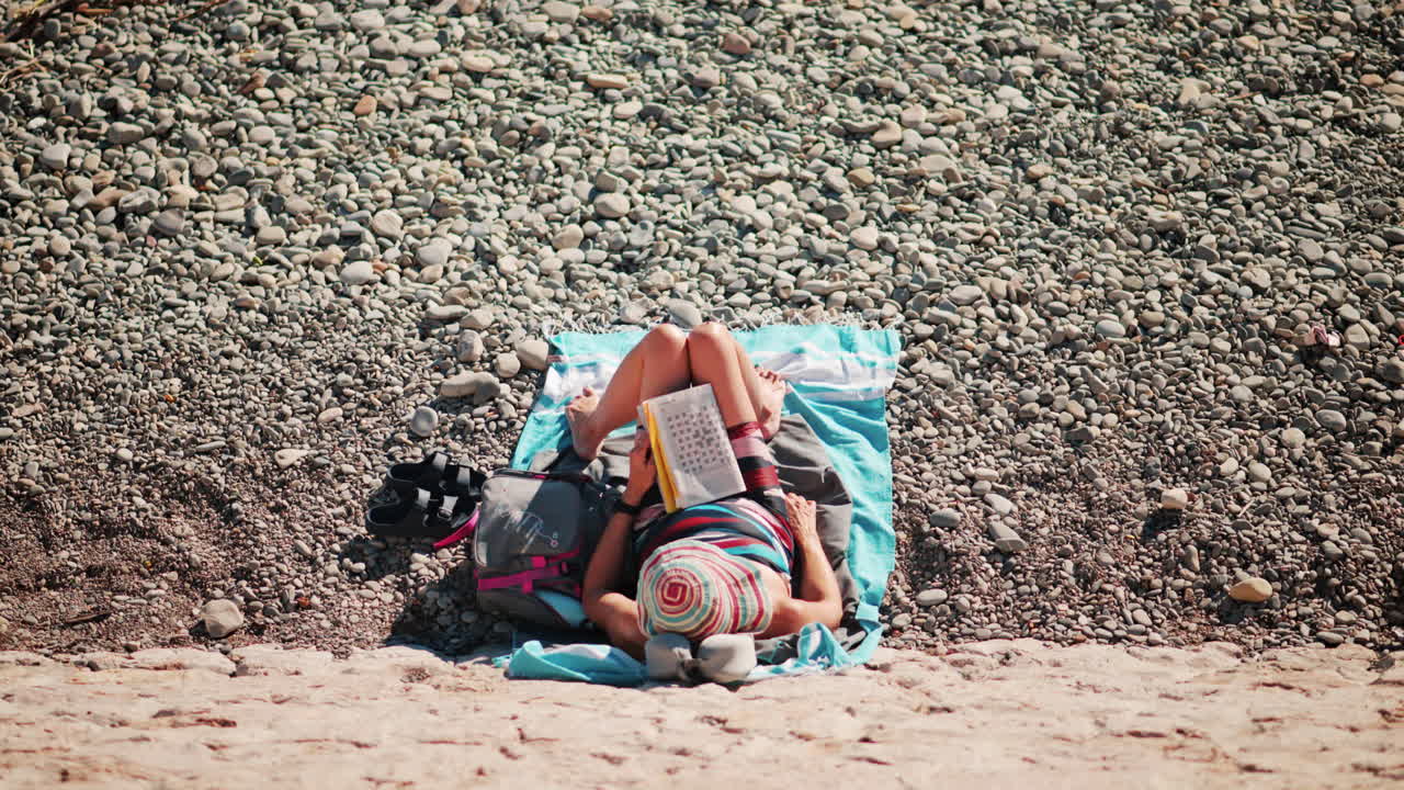 High angle view of a woman reading on a towel at the beach in Nice, France