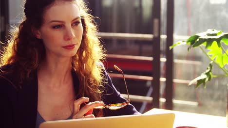 female executive using laptop while having coffee