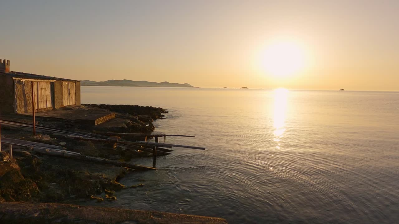 석양에 열대 섬 해안에서 낮고 바다 가까이 날아가는 드론