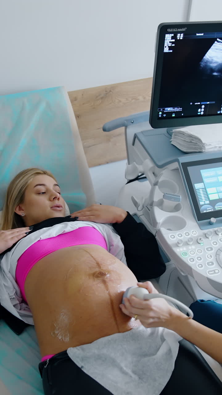 Obstetrician says something to a lady during the ultrasonic check up. Doctor looks at the monitor and explaining it to a patient. Vertical video