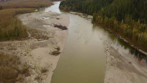 Aerial-view-flying-over-a-river-flowing-through-a-mountain-wilderness