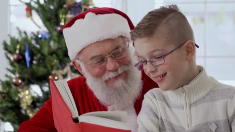 santa claus and little boy read the book and laughing