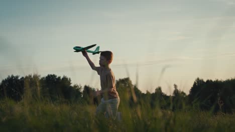 little boy running with toy airplane at meadow.