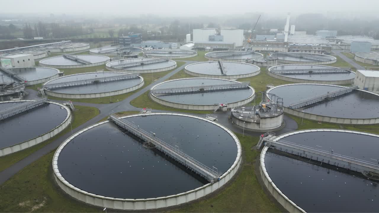 Drone aerial of large circular wastewater treatment basins in Rijswijk, Netherlands during foggy morning conditions