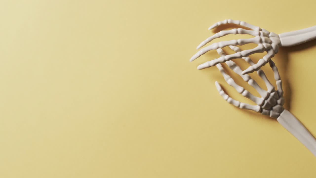 video de las manos del esqueleto de halloween con espacio de copia en fondo amarillo
