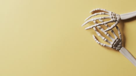 video di mani di scheletro di halloween con spazio di copia su sfondo giallo