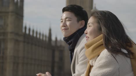 young asian couple on holiday visiting houses of parliament in london uk