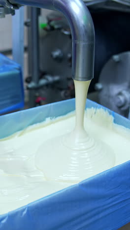 processing of butter at dairy plant. butter pouring from the pipe into the container