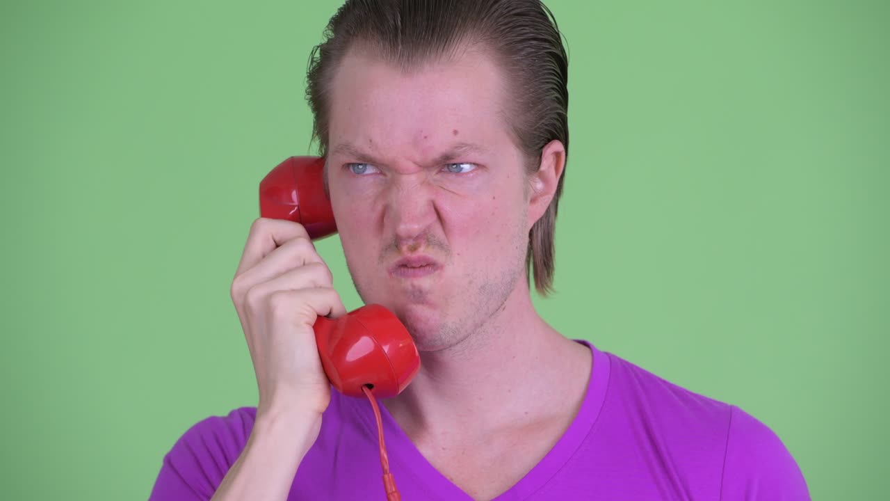 fotografía de estudio de un joven enojado hablando por teléfono, zoom out, fotografía contra un fondo verde