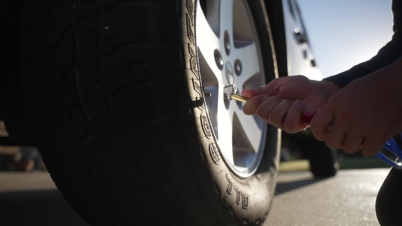 Medium shot of inflating an SUV tire using a handheld air hose