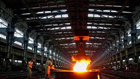 steel melting process at a large industrial facility in the evening with workers overseeing operations