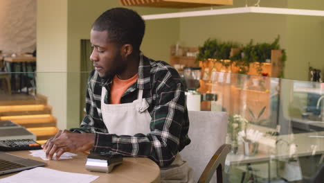 two multiethnic coffee shop owners calculating finance bills on laptop computer