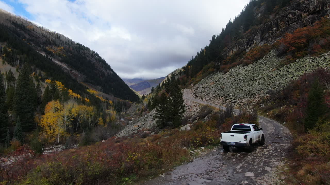 cinematográfico drone aéreo 4wd camión fuera de carretera mármol molino de cristal otoño impresionante aspen colores de otoño sur de colorado montañas rocosas picos ouray telluride acampada por el río árboles amarillos lentamente hacia adelante