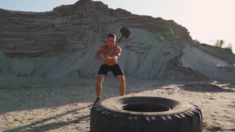 El-Hombre-Fuerte-Del-Atleta-Muscular-Golpea-Un-Martillo-En-Una-Rueda-Enorme-En-Las-Montañas-Arenosas-En-Cámara-Lenta.-Entrenamiento-De-Fuerza-Y-Resistencia-Para-Luchadores.