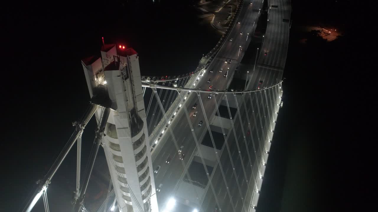 toma aérea de vehículos que se desplazan por el puente de la bahía de san francisco–oakland con la ciudad de fondo por la noche