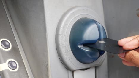 person inserting a credit card into an atm machine