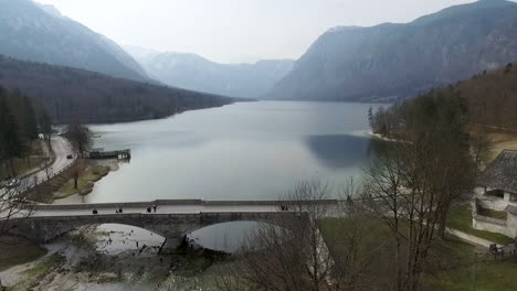 Drone-view-of-bridge-and-church-from-the-Bohinj-lake,-Slovenia