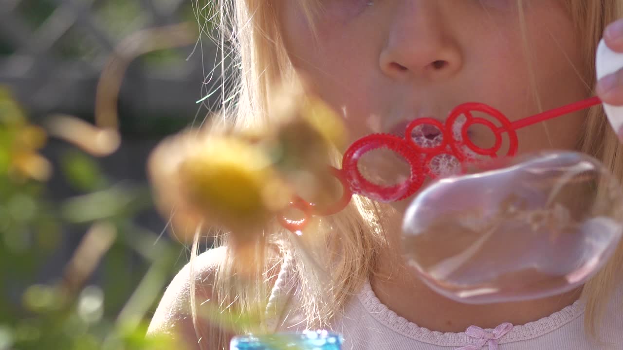 Blonde summer girl blows bubbles with wand