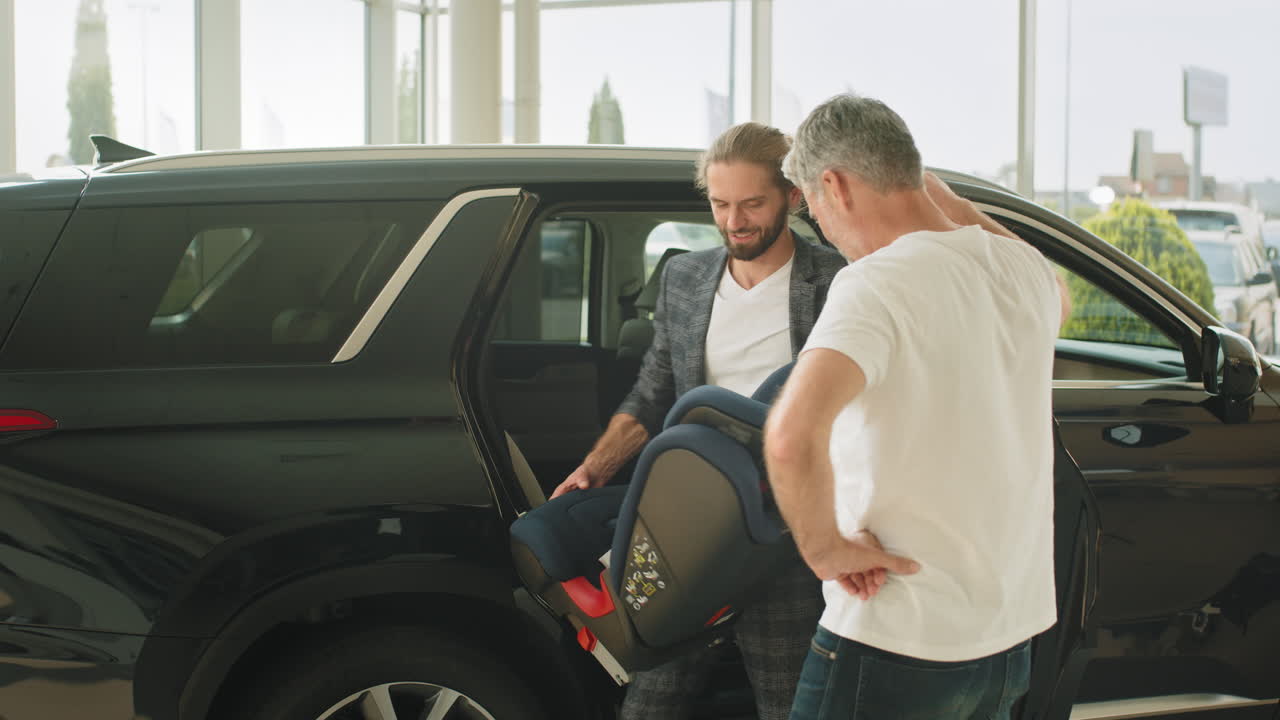 vendedor de automóviles mostrando la instalación del asiento de automóvil a un cliente