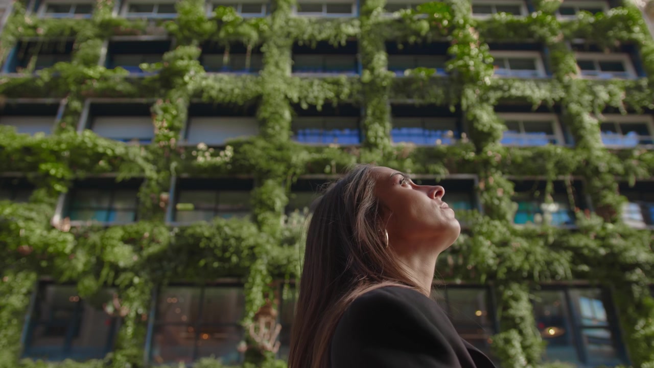 Jovem mulher morena passando pelo hotel Villa M coberto de plantas em Paris, França