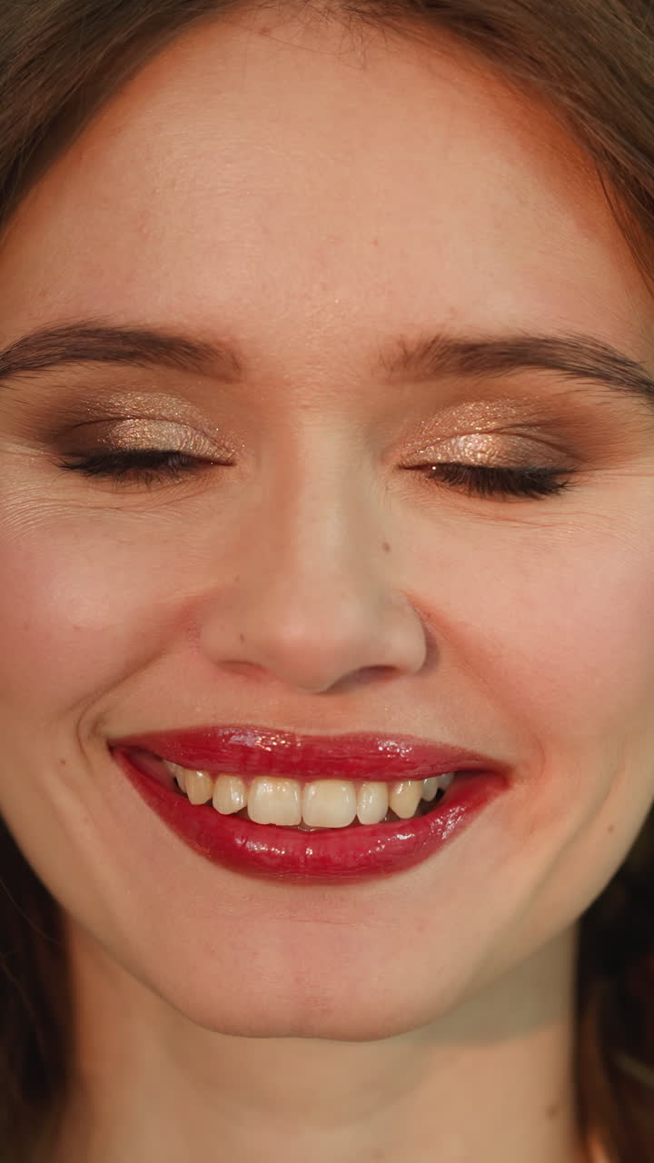 Young woman with professional makeup looks in camera smiling. Portrait of positive female person with ginger hair on blurred background closeup