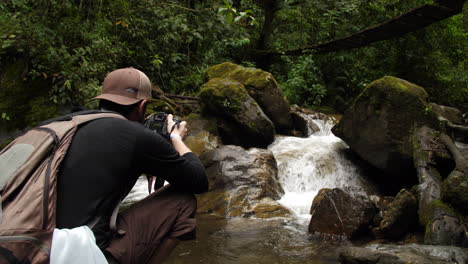 photographer taking pictures of a river running under a bridge in the jungle