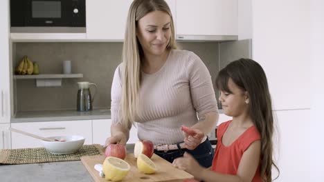 madre alegre cortando manzanas frescas en la cocina