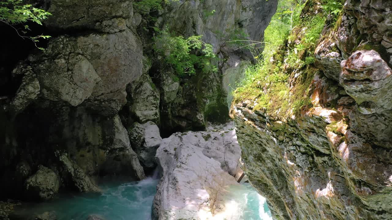 Dolly out of dramatic turquoise Soca RIver flowing rapidly between rocks near Boka Waterfall, Slovenia