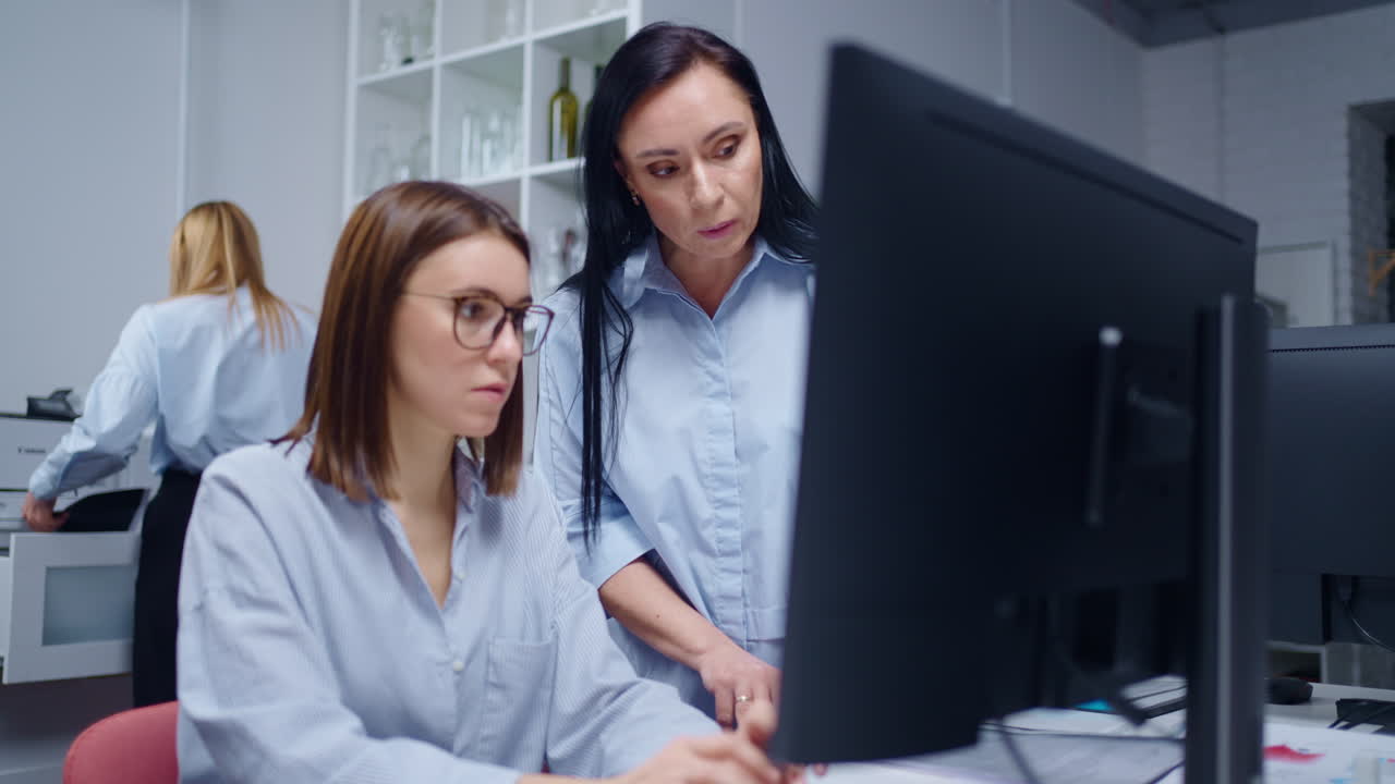 dos mujeres de negocios trabajando en una computadora en una oficina