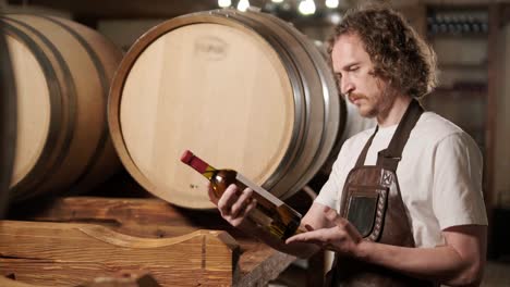 authentic shot of successful male sommelier is tasting a flavor and checking white wine quality poured in transparent glass in a wine cellar.