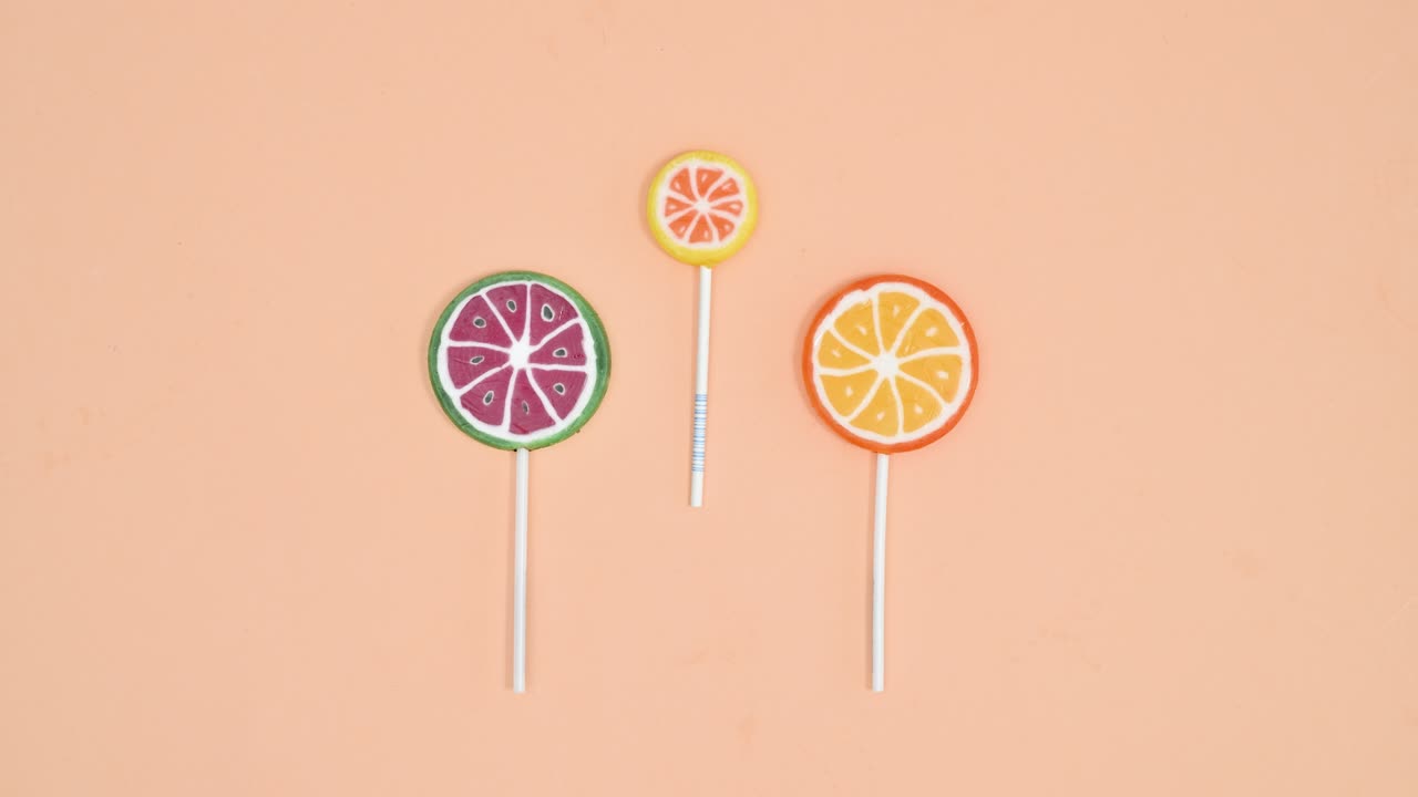 animación de stop motion creativa de piruletas frutales en un fondo naranja pastel brillante. stop motion lay plano