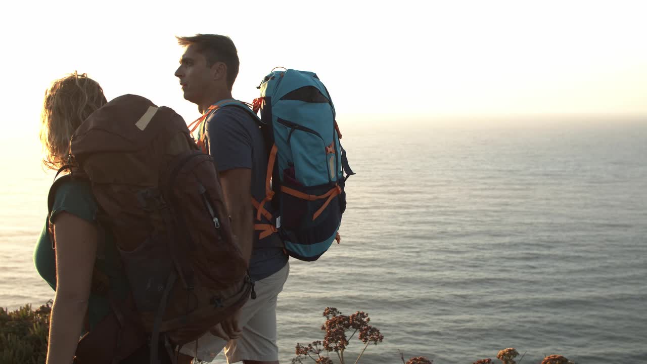 pareja feliz con mochilas de campamento caminando por el camino de la montaña