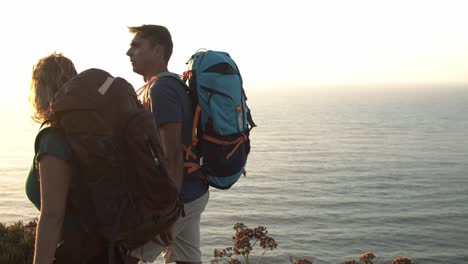 Happy-couple-with-camping-backpacks-walking-on-mountain-path